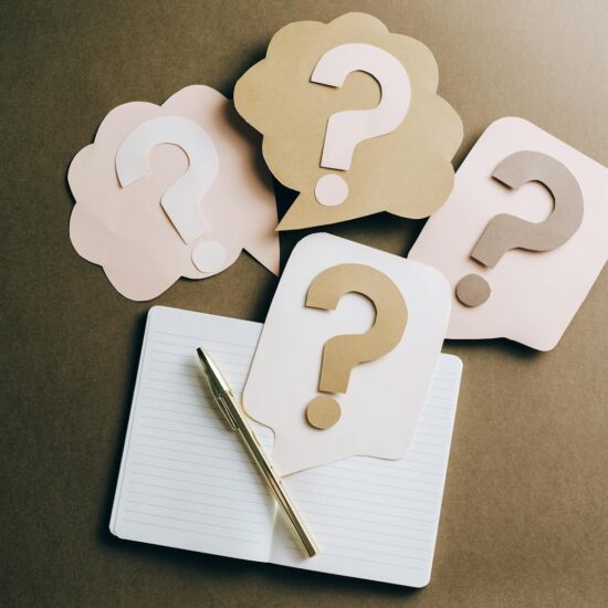 Flat lay of question mark paper crafts on a notebook, symbolizing questions and ideas.