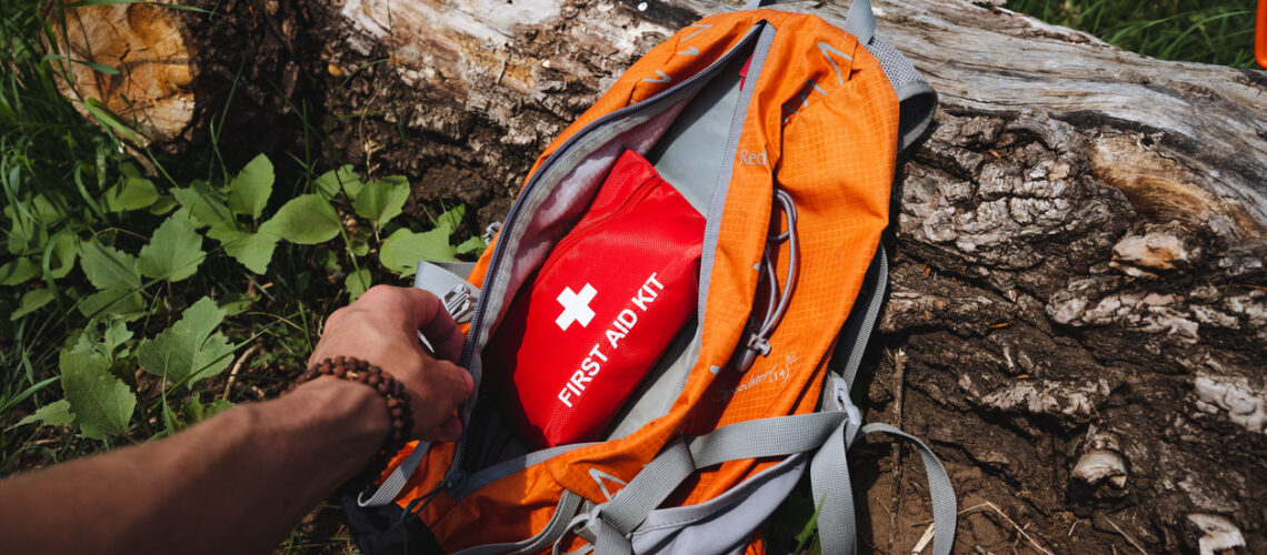 A first aid kit is in a backpack, a tourist in the forest takes a first aid kit out of his bag, safety in nature. High quality photo