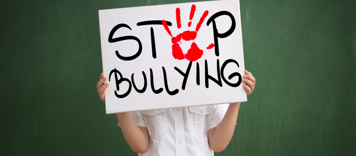 Boy holding a sign with red palm print and text stop bullying